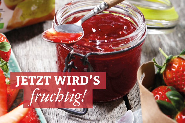 Marmeladenglas mit einer fruchtigen, roten Erdbeermarmelade und frischen Erdbeeren